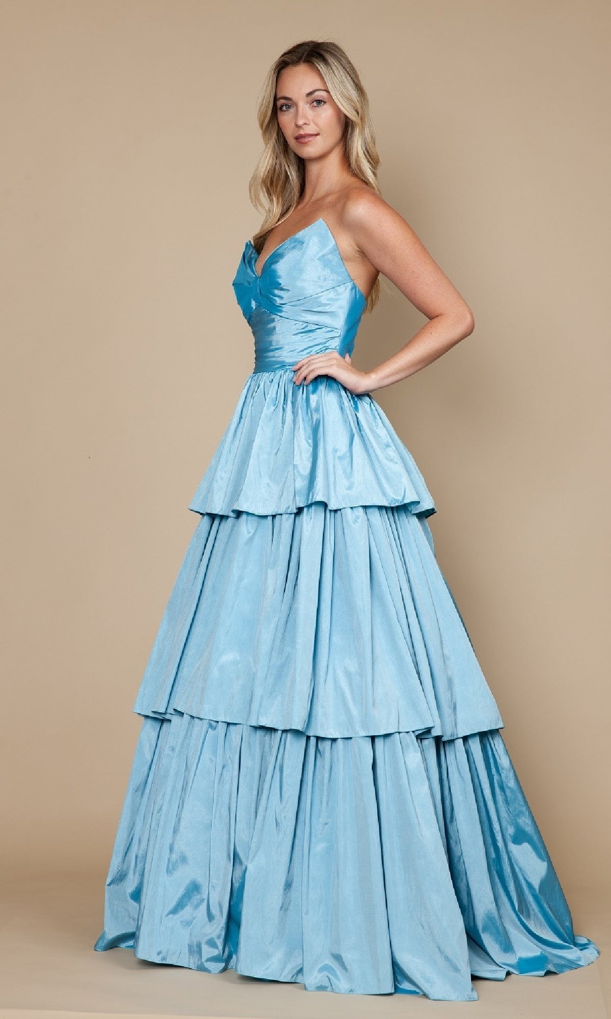 A woman models the Long Prom Dress: Poly USA 9694—a light blue, strapless gown with tiered layers and an elegant A-line silhouette—against a plain beige background.